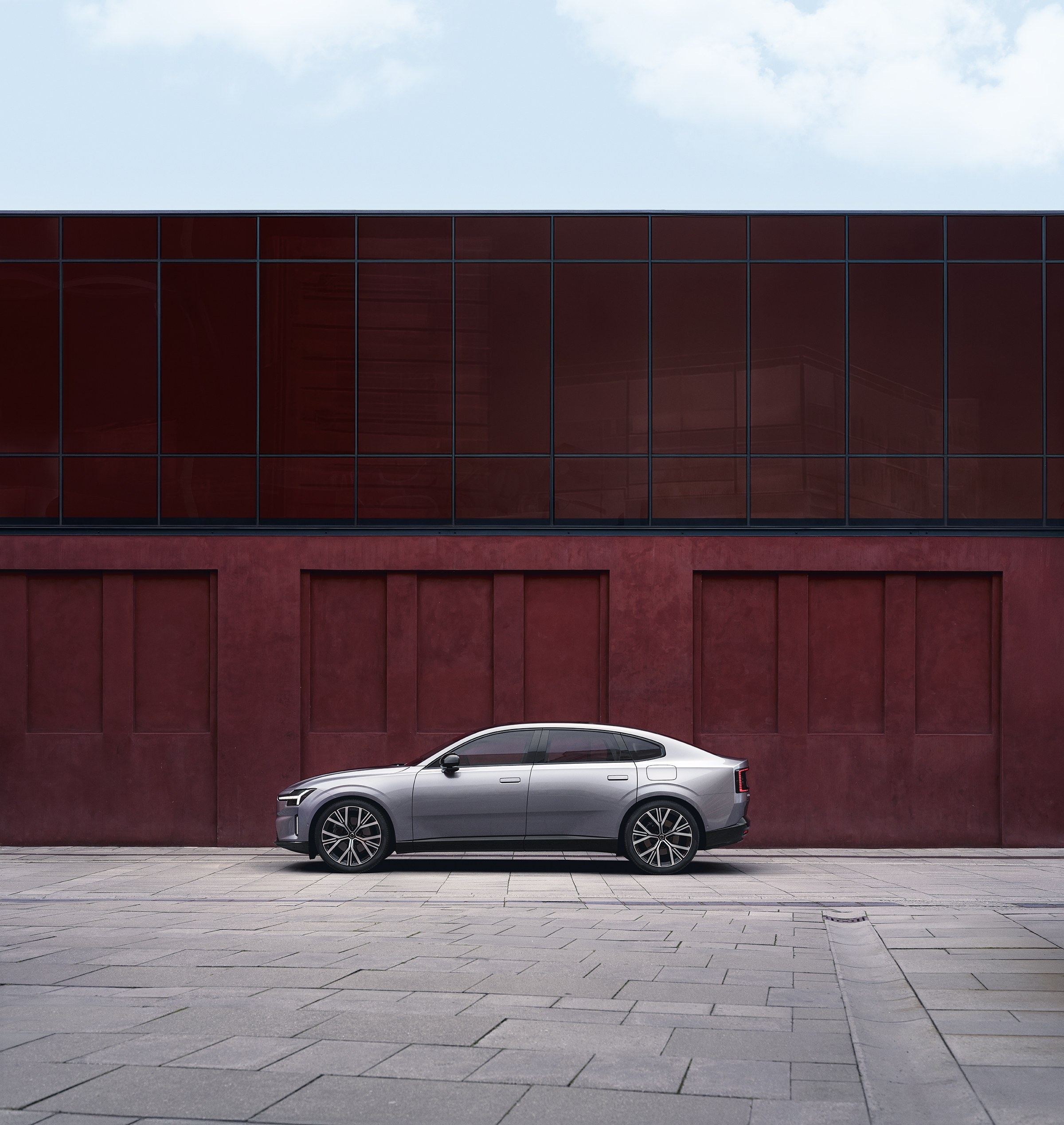 Volvo ES90 in der Seitenansicht vor einer roten Wand