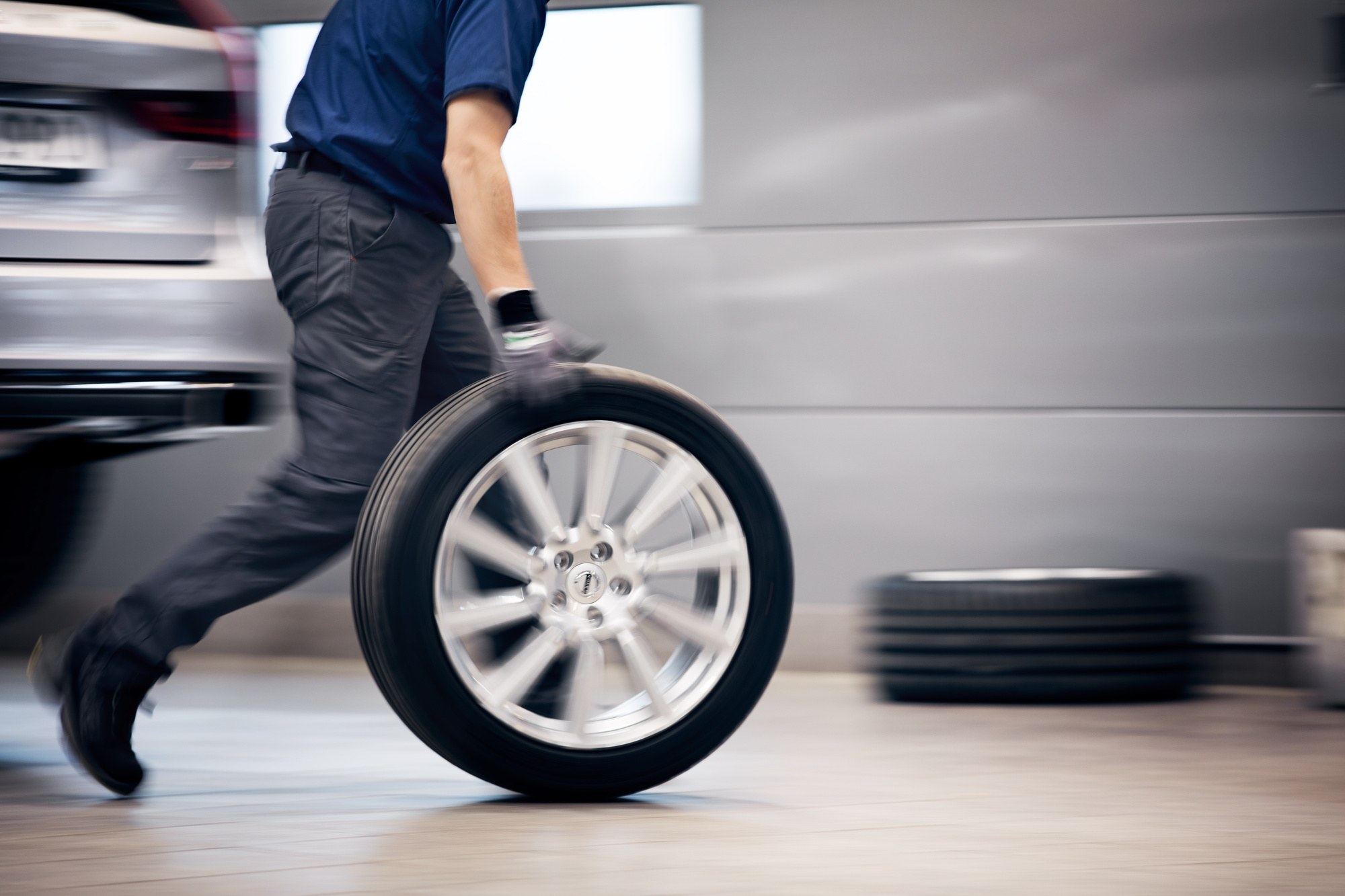 Mechaniker rollt ein Rad durch die Werkstatt