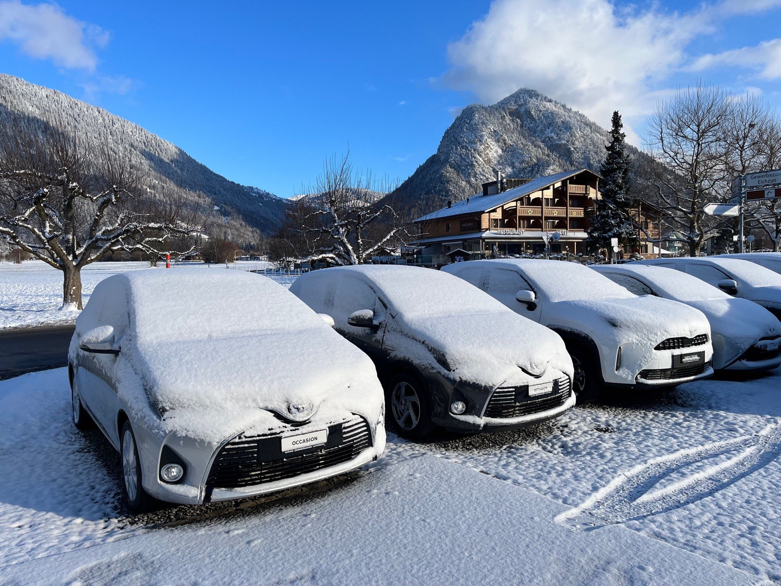 Verschneite Fahrzeuge vor der Garage im Winter